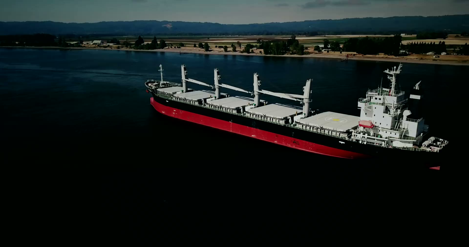 A red-hulled bulk carrier under way on a river