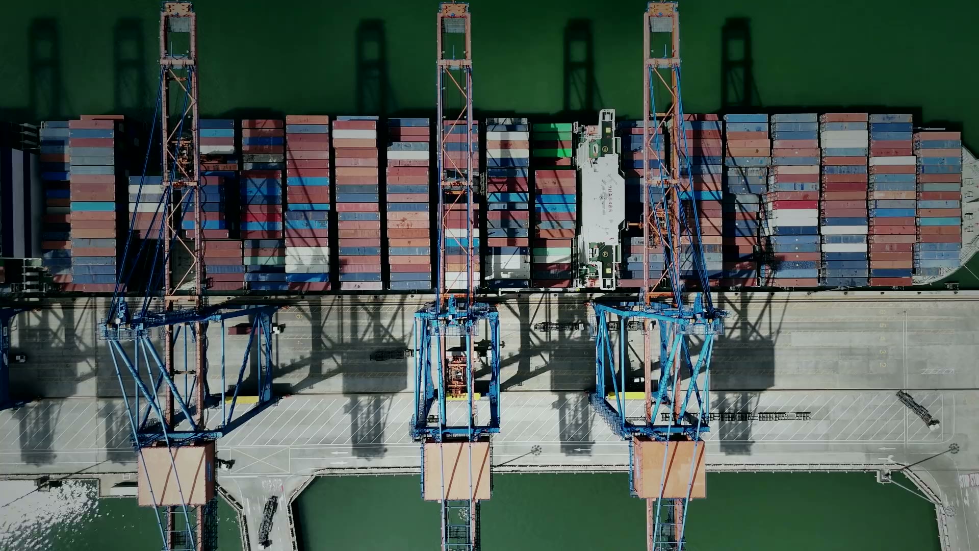 A container ship under quay cranes, seen from above
